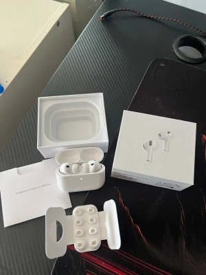 Apple AirPods Pro 2 med laddningsetui - Säljer ett par vita Apple AirPods Pro 3 2025 med trådlöst laddningsetui. Hörlurarna har silikonproppar i olika storlekar och levereras i originalförpackning med tillbehör. Snygg och stilren design i blank plast, perfekt för dig som vill ha grymt ljud och smidig anslutning.