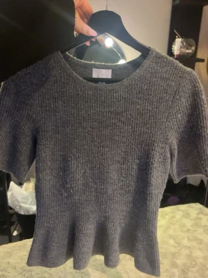 Grå Stickad Topp - Säljer en grå stickad topp med volang i nedkant och korta ärmar 💗Från H&M, använd 1-2 ggr. I jätte fint skick !! 