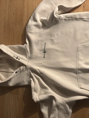 Vit hoodie från Sail Racing - Säljer en vit hoodie från Sail Racing med logga tryckt på bröstet. Hoodien har en stor ficka framtill och justerbar huva med snören. Tillverkad i mjukt bomullsmaterial som är skönt att ha på sig. Perfekt för dig som gillar enkel och clean stil. Passar xs s och även kanske m. 