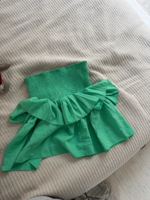 Grön volangig bandeau topp - Snygg grön bandeau topp med volangdetaljer och smockad överdel. 