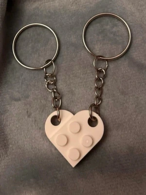 Nyckelring legobitar hjärta nyckelringar för par  - Ett gulligt par nyckelringar med var sin legobit som tillsammans bildar ett hjärta! Fint att dela med sin bästis, partner eller någon annan som betyder mycket. Varje legobit är ca 2 x 1,5 cm och hela nyckelringen är ca 6,5 cm lång.