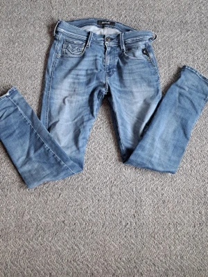 Blå slim fit jeans från Replay - Snygga blå slim fit jeans från Replay med klassisk femficksmodell och ljus tvätt. Jeansen har detaljerade sömmar på bakfickorna och ett Replay-märke i läder baktill i midjan. Tillverkade i mjuk denim med stretch för extra komfort. Använda väldigt få gånger! 30W L30