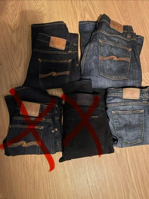 Blå jeans från Nudie Jeans - Säljer flera par klassiska blå jeans från Nudie Jeans med den ikoniska vågade sömmen på bakfickorna och läderpatch i midjan. Jeansen har rak passform och är tillverkade i slitstarkt denimtyg. Perfekta för en avslappnad och trendig stil. Alla för 600kr eller 250kr styck
