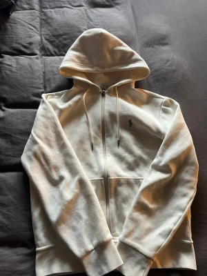 Vit hoodie med dragkedja från Polo Ralph Lauren - Snygg vit hoodie från Polo Ralph Lauren. Köpt på NK i Stockholm för 2500kr otroligt bra skick strl S passar 170-180 cm. Har kvitto