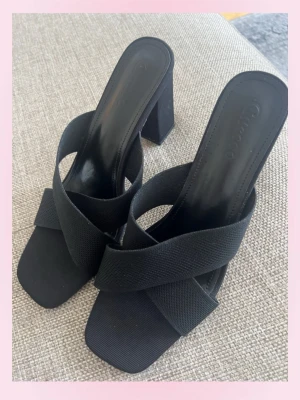 Svarta klackar - 💓💓Säljer ett par svarta klackar med breda korsade band . Skorna har fyrkantig tå och är tillverkade i textilmaterial med en stilren look. Perfekta för dig som gillar trendiga och bekväma klackar.💕💞