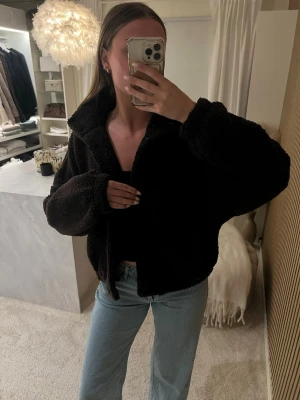 Mörkbrun teddyjacka från H&M - Säljer en mörkbrun teddyjacka med oversized passform och stor krage. Jackan är fluffig och mjuk, har långa ärmar och stängs framtill med knappar. Perfekt för dig som vill ha en mysig och trendig look till hösten eller vintern.