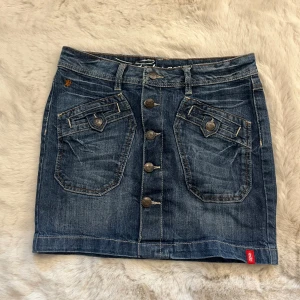 Lågmidjad jeanskjol från edc by Esprit - Snygg blå jeanskjol från edc by Esprit med coola fickor fram och bak, samt knappar hela vägen framtill. 