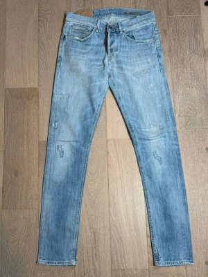 Ljusblå skinny jeans från dondup George. - Säljer ett par ljusblå skinny jeans med coola slitningar och tvättade detaljer. Jeansen har klassisk femficksmodell, normal midja och smala ben. Perfekta för en avslappnad och trendig look.Dondup George Model Jeans Size W32 Length 101 cm