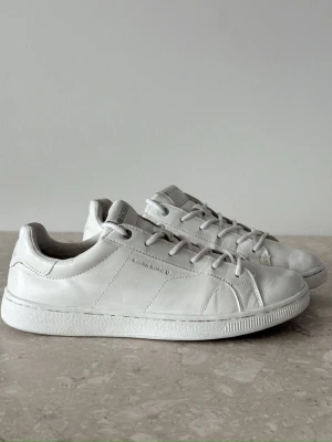 Björn Borg white sneakers | EU 40  - Stilrena vita sneakers från Björn Borg i mjukt läder med klassisk låg profil. Skorna har vita snören, diskret logga på sidan och en vit sula. Perfekta för dig som gillar en clean och enkel look. Passar till det mesta och är lätta att matcha.