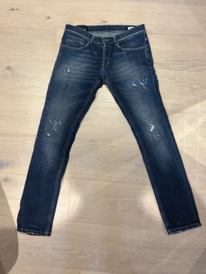 Dondup jeans - Snygga mörkblå skinny jeans med slitningar och lätt tvättade detaljer på låren och knäna. Klassisk femficksmodell med dragkedja och knapp i midjan. Jeansen har en modern, smal passform och är perfekta för en trendig vardagslook.