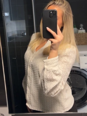 Vit blus med strukturmönster - Säljer en vit blus med snygg struktur och diskreta prickar i tyget. Blusen har v-ringning, knäppning framtill och långa puffiga ärmar. Sparsamt använd 🩷