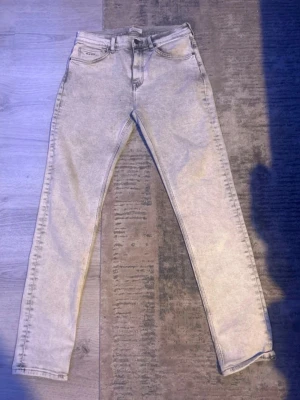 Gant Ljusgrå slim jeans  - Säljer ett par ljusgrå skinny jeans med hög midja och klassisk femficksmodell. Jeansen har en tvättad look och smala ben som sitter tight hela vägen ner. Perfekta att matcha med en oversized hoodie eller crop top.