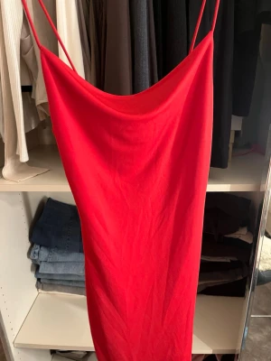 Röd klänning från Bik Bok - Snygg röd klänning från Bik Bok med tunna axelband och draperad urringning. Klänningen har en smal passform och är tillverkad i ett mjukt, stretchigt material som sitter bekvämt mot kroppen. Perfekt för dig som vill sticka ut med en enkel men elegant look.