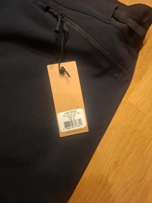 Svarta cykelshorts från Specialized - Snygga svarta cykelshorts från Specialized med dragkedjeförsedd ficka framtill och justerbar midja. Tillverkade i ett slitstarkt syntetmaterial som passar perfekt för träning och cykling. Klassisk design med knäppning och bekväm passform.