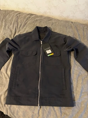 Svart overshirt Elvine - Helt ny overshirt, bara testad. Köptes i danmark men den blev för liten nu. Jackan har två dragkedjor och är tillverkad i ett slitstarkt material som passar perfekt för lager-på-lager och är dessutom vattentät! Storlek S. Hör av er för mer info 😁