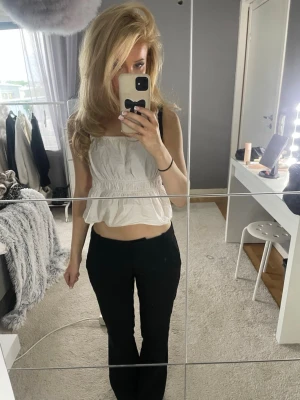 Svarta utsvängda kostymbyxor - Säljer ett par svarta kostymbyxor med utsvängda ben och hög midja. Byxorna har en klassisk look och är perfekta för en stilren outfit. Materialet ser ut att vara mjukt och följsamt, vilket ger en snygg passform.
