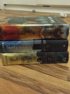 The Mortal Instruments trilogi - Säljer de tre första böckerna i The Mortal Instruments-serien: Stad av skuggor, Stad av aska och Stad av glas. Inbundna med färgstarka omslag i grönt, blått och orange. Perfekt för dig som gillar urban fantasy och spännande äventyr.