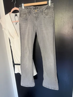 Grå bootcut jeans från LTB - Snygga grå bootcut jeans från LTB med klassisk femficksdesign och låg midja. Storlek 27/30. Jeansen har en lätt tvättad look och är tillverkade i mjukt denimtyg med stretch för extra komfort. Perfekta för dig som gillar en avslappnad men trendig stil.