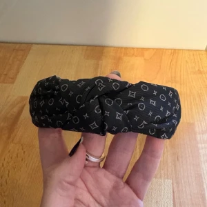 Diadem - Diadem med mönster på. Själva färgen på mönstret tycker jag ser grått ut, med lite skiftning i lila. Men färgen på bilderna visar bra. Knut uppe på. Aldrig använt!