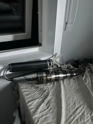 Yasuni z (sprillans) - Ett riktigt fint yasuni z rör som endast blivit använt en vecka. Super fint glans och funkar perfekt! Ett riktigt bra rör för både 50 och 70 kubiks cylindrar. Riktigt fräsch och står ut ifrån många andra avgasrör med en kolfiber dämpare. OBS! för liggande minarelli motorer som ex: jog r, Neos, aerox m.m