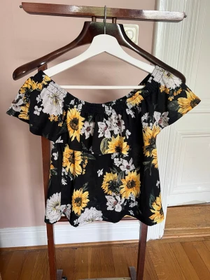 Blommig offshoulder topp Gina Tricot - Supersöt offshoulder topp från Gina Tricot med stort blommigt mönster i gult och vitt på svart botten. Jättefin till sommaren💗💗🌼🌼
