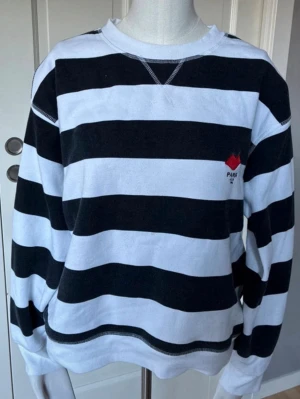 Randig svartvit sweatshirt - Säljer sweatshirt med breda svarta och vita ränder. Tröjan har rund halsringning och en liten röd detalj på bröstet. Tillverkad i mjukt bomullsmaterial och har långa ärmar. Säljer pga att den inte används och storleken kan upplevas som xs/s💓