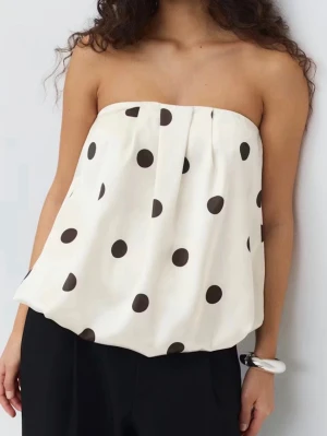 Prickig vit axelbandslös tubtopp - Snygg axelbandslös tubtopp i vitt med stora svarta prickar. Använd total gånger. Pris kan diskuteras. Skriv om ni är intresserade och vill ha egna foton🥰🥰