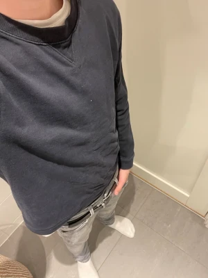 Mörkblå sweatshirt med patch - En enkel och stilren mörkblå sweatshirt med rund hals och ribbade muddar. Tröjan har en vit patch på ena ärmen som detalj. Perfekt för en avslappnad och casual look. Tillverkad i mjukt bomullsmaterial och har lång ärm.