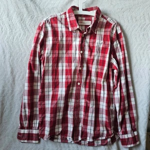 Rödvit rutig skjorta från Levi's - Klassisk röd och vit rutig skjorta från Levi's med lång ärm och knappar framtill. Skjortan har en avslappnad passform och är tillverkad i mjuk bomull, perfekt för en casual look. Snygg krage och tidlös design som funkar året runt.