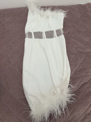 Vit one shoulder klänning - Använder ej! En vit kortklänning med one shoulder-design och transparent meshdetalj i midjan. Perfekt för dig som vill sticka ut på festen. 