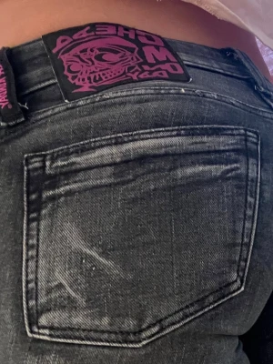 Gråa jeans från Cheap Monday - Säljer ett par gråa jeans från Cheap Monday. Jeansen har en cool tvättad look och ett svart-lila märke med döskalle bak i midjan. Perfekta för dig som gillar streetstyle och vill ha något unikt i garderoben.