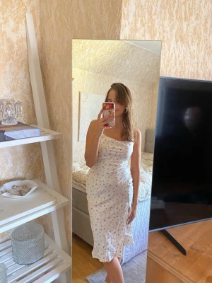  Blommig satin midiklänning med slits - Blommig satin midiklänning med slits och öppen rygg med knytning. Endast använd en gång, i fint skick! 