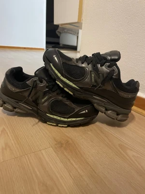 Svarta New Balance 2002R sneakers - Snygga svarta New Balance 2002R sneakers med meshpaneler och detaljer i syntetläder. Skorna har en chunky sula med grå och gröna inslag samt klassisk N-logga på sidan. Perfekta för dig som gillar streetwear och sportig stil.