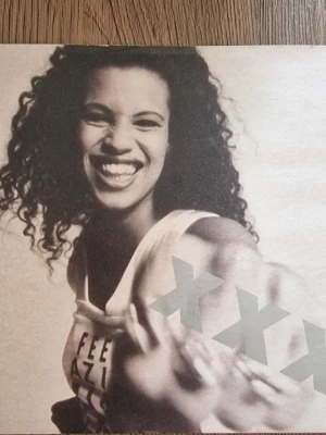 Neneh Cherry Kisses Lp singel - LP singel 'Neneh Cherry Kisses' i stora bokstäver. Omslaget har en modern och grafisk design med stora grå X och text över bilden. Perfekt för dig som gillar musikrelaterat.