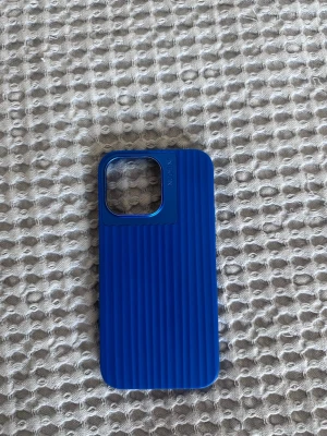 Blått mobilskal från Nudient - Snyggt blått mobilskal från Nudient med räfflad yta och robust design. Skalet har en stor öppning för kameran och är gjort i tålig plast. Perfekt för dig som vill ha ett stilrent och skyddande skal till din mobil. Måtten är 15 cm i längden och 8 cm i bredden.