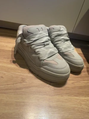 Beige sneakers med chunky sula - Snygga beige sneakers med chunky sula och breda vita skosnören. Skorna har en stilren design med paneler i mockaimitation och meshdetaljer på ovandelen. Perfekta för dig som gillar en clean och modern look.