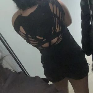 Svart croppad topp med slitsad rygg - Cool svart croppad topp med slitsad och öppen rygg. Toppen är ärmlös och har ett edgy, trendigt utseende som passar perfekt till jeans eller kjol. Materialet känns mjukt och stretchigt, troligen bomull eller polyester.