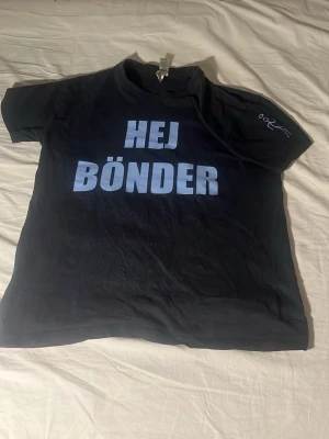 Dif t-shirt med tryck 'HEJ BÖNDER' - Cool blå t-shirt med stort vitt tryck 'HEJ BÖNDER' på framsidan och 'VI É DIF' på baksidan. Klassisk passform och rund hals. Perfekt för dig som vill sticka ut på matchen eller i vardagen.
