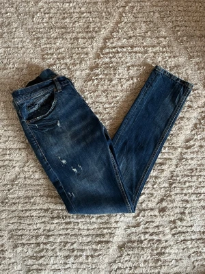 Dondup George jeans - Säljer just nu dessa otroligt feta Dondup George jeans i nyaste årsmodellen i en riktig fin blå färg med unika slitningar. Jeansen är i storlek 30. Midja 38cm. Lår 25cm. Ytterlängd 103cm. Innerlängd 80cm. Skicket på dessa är 9/10 inga skador eller defekter. För fler frågor eller funderingar är det bara att höra av sig. 