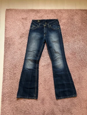 Lee Felton Bootcut Jeans - Lee Bootcut Jeans, modellnamn Felton. Storleken är W28 L31. Jeansen är inte i stretch. Bra skick, men de är lite slitna nere vid benen och så är båda framfickorna tyvärr uppklippta. Tveka inte på att höra av dig vid funderingar!⭐️