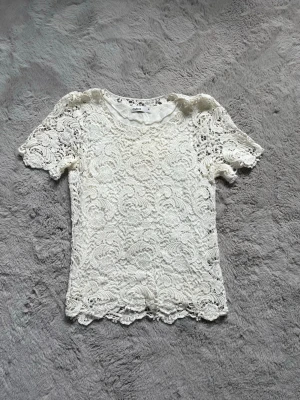 Vit spetsblus från Cubus - Säljer en superfin vit spetsblus från Cubus i storlek 36. Blusen har korta ärmar och ett detaljerat spetsmönster över hela plagget. Perfekt att styla med jeans eller kjol för en trendig look!