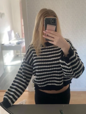 Randig svartvit stickad tröja - Säljer en tunt stickad tröja med svarta och vita ränder. Tröjan har en croppad passform, långa ärmar och ribbade kanter. Perfekt för dig som gillar en avslappnad och trendig stil. Materialet är mjukt och fluffigt, vilket gör den extra mysig.