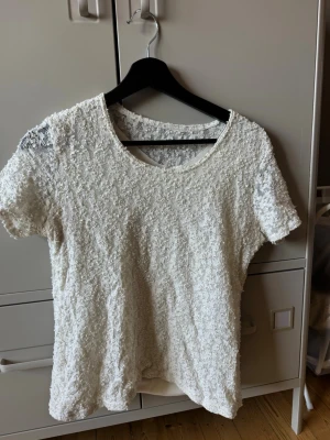 Vit spetsblus med kort ärm - Säljer en söt vit blus med kort ärm och rund halsringning. Har använts en del därav lågt pris. Finns ingen lapp så vet ej var den är ifrån. Troligen storlek M 