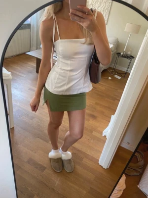 Superfin olivgrön minikjol  - Säljer denna superfinna olivgröna minikjol! Den har en stilren passform och en liten slits framtill som ger en snygg och trendig look. Perfekt både till vardags och fest🤍