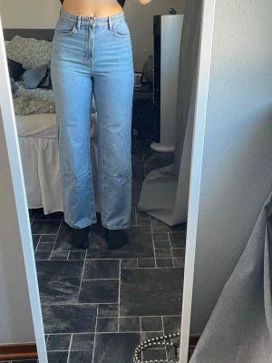 Ljusblå raka jeans med hög midja - Säljer ett par ljusblå jeans med hög midja och raka ben. Har använts ett fåtal gånger och har två små hål på ena bakbenet, se bild. Säljer dem då de är för små. Är 174cm för referens💕