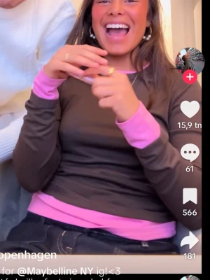 Brun långärmad topp med rosa detaljer - Trendig brun långärmad topp med kontrasterande rosa muddar och rosa undertröja som sticker fram vid hals, ärmslut och midja. Perfekt för dig som gillar färgkombinationer och lager på lager-stil.