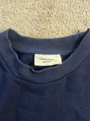 Mörkblå sweatshirt från Gina Tricot - En enkel och stilren mörkblå sweatshirt från Gina Tricot, basically basics-kollektionen. Tröjan har rund halsringning, ribbade muddar vid ärmslut och nederkant samt en avslappnad passform. Perfekt för en chill och casual look.