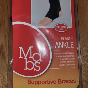Elastiskt fotledsbandage Mabs - Elastiskt fotledsbandage från Mabs i svart material. Ger stöd runt ankeln och är designad för att vara bekväm och smidig att bära. Passar både höger och vänster fot och har en enkel, diskret design. Perfekt för dig som behöver extra support vid träning eller vardag.