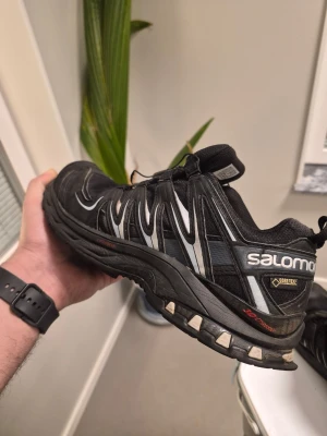 Salomon XA Pro 3D GTX, Träningsskor, Svart, 41 1/3 - Säljer ett par svarta Salomon kängor med Gore-Tex membran och snabbsnörning. Modellen är XA Pro 3D, kända för sin slitstarka sula och bekväma passform. Skorna har detaljer i vitt och grått samt robust design som passar perfekt för utomhusaktiviteter.