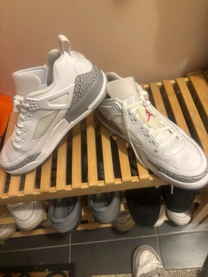 Vita Air Jordan sneakers med grå detaljer - Säljer ett par vita Air Jordan sneakers med grå elefantmönstrade detaljer och röd Jumpman-logga på plösen. Skorna har en hög siluett, klassiska snörningar och är tillverkade i läder och mesh för en sportig look. Pris kan diskuteras 